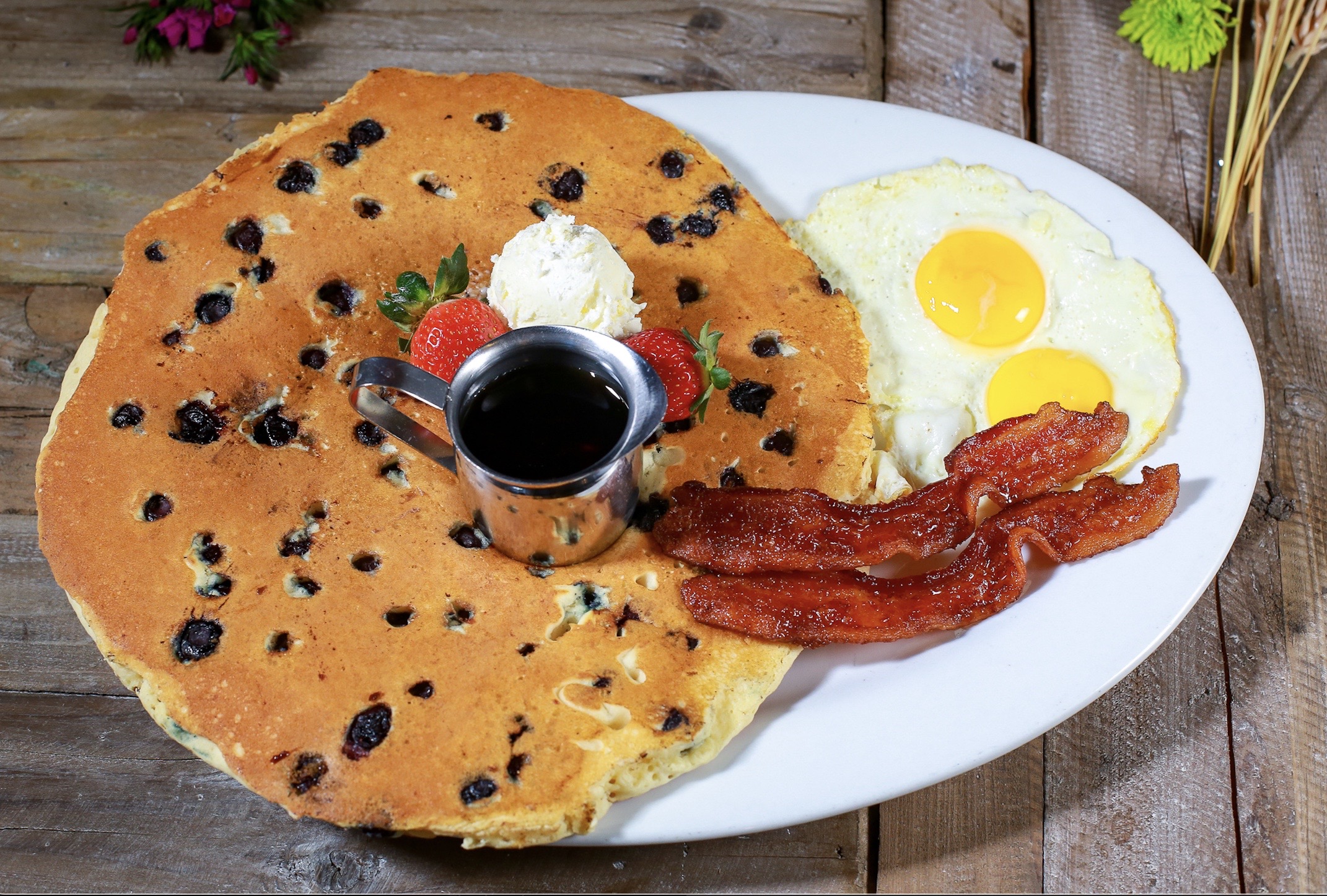 Massive chocolate chip pancake breakfast with eggs, bacon, and syrup at Hash House A Go Go Flamingo in Las Vegas.