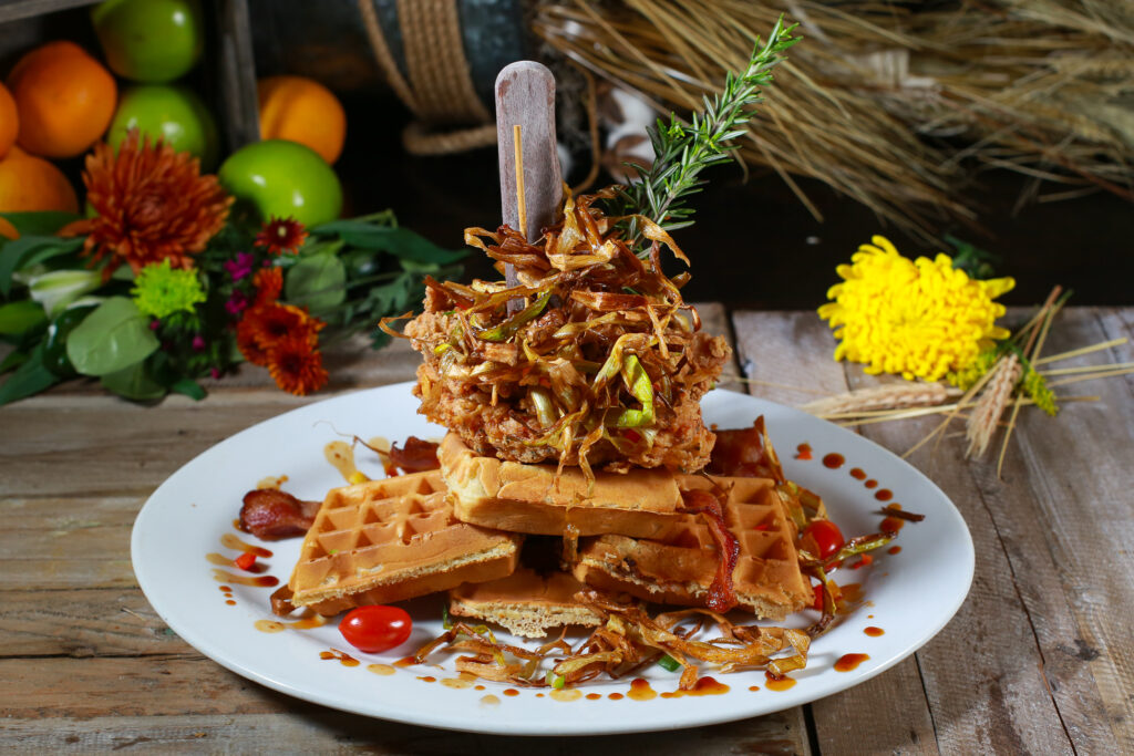 Discover the Unique Brunch Experience at Hash House A Go Go Flamingo 10 unique fried chicken and waffle tower from Hash House A Go Go in Downtown Las Vegas, topped with crispy leeks and garnished with rosemary.