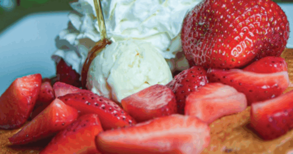 Summer Menu From Mimosa Flights to Hoe ‘Cakes: A Brunch Lover’s Guide to Hash House Flamingo 1 Stack of Johnny Hoe Cakes topped with whipped cream, strawberries, and syrup at Hash House Flamingo Crossings