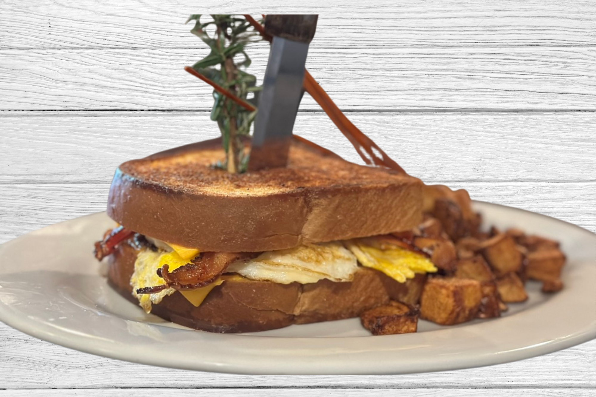 Gourmet breakfast sandwich with bacon, egg, and cheese on toasted bread served with crispy breakfast potatoes at Las Vegas brunch restaurant.