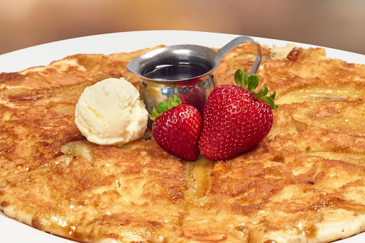 Golden griddled breakfast dish topped with fresh strawberries and butter, served with syrup on a white plate served at Hash House A Go Go Flamingo Crossing.